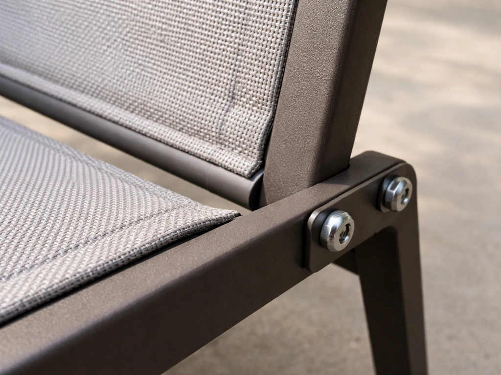 Close-up of a sling chair joint where the fabric is seated in a rail groove and the rail is bolted to the frame